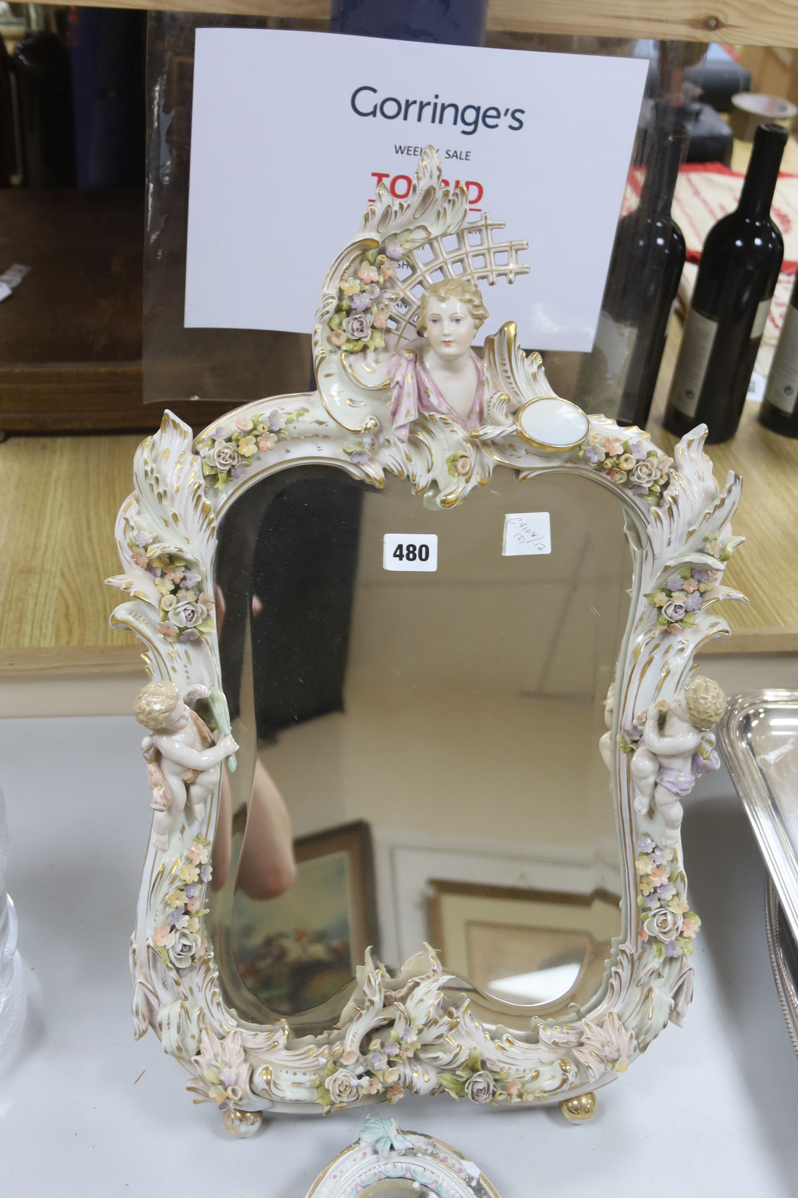 A large 19th century German porcelain easel mirror, height 60cm, and a smaller oval porcelain mirror